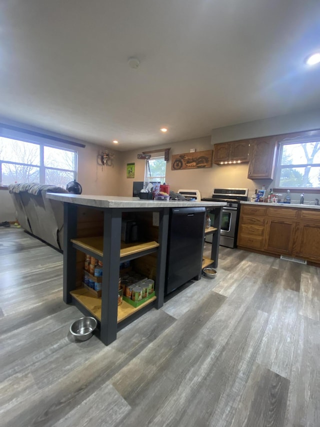 kitchen with stainless steel range, a breakfast bar, hardwood / wood-style flooring, and a wealth of natural light