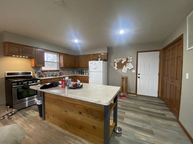 kitchen with hardwood / wood-style flooring, white refrigerator, sink, and gas range