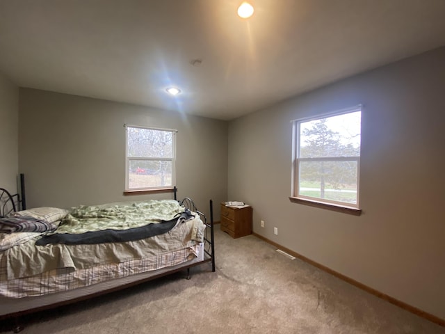 bedroom with light colored carpet and multiple windows