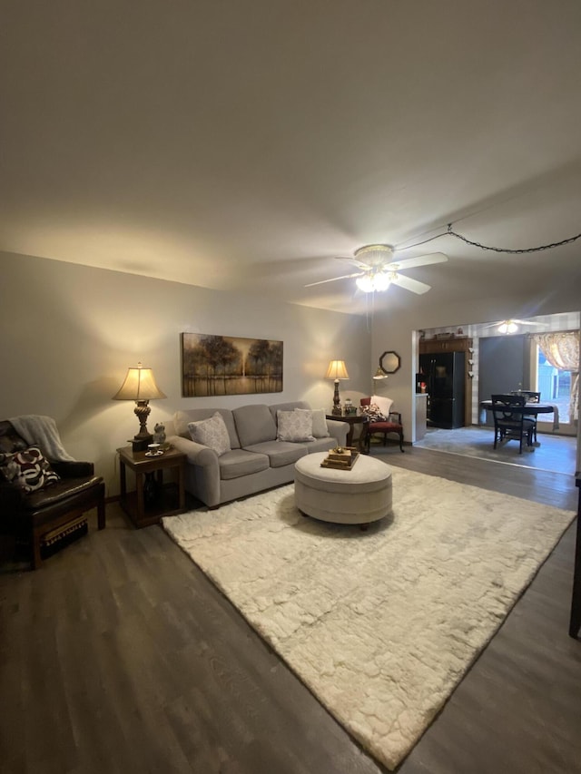 living room with ceiling fan and dark wood-type flooring