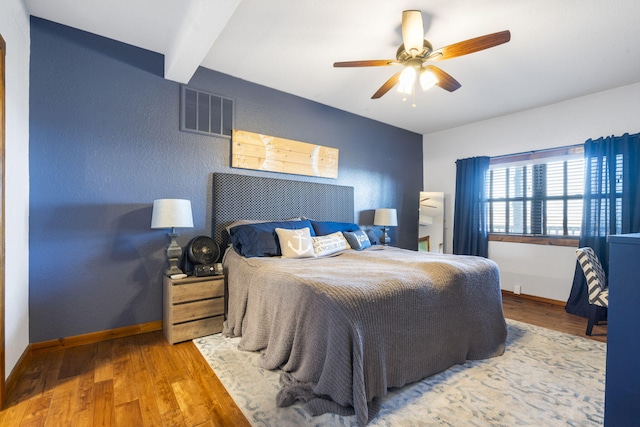 bedroom featuring hardwood / wood-style floors, beamed ceiling, and ceiling fan