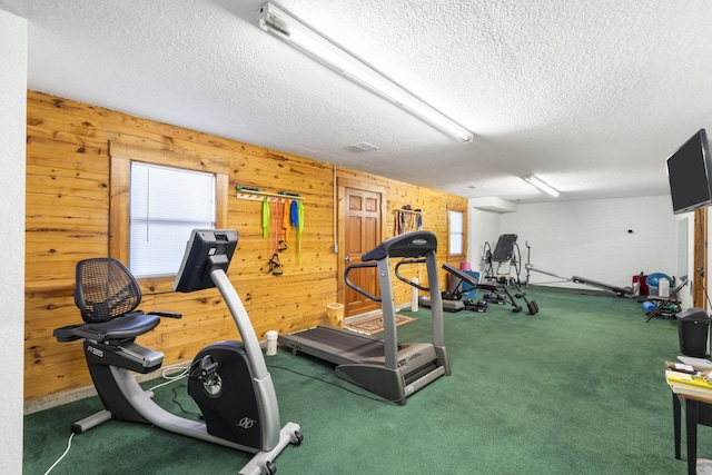 exercise area with wooden walls, carpet flooring, and a textured ceiling