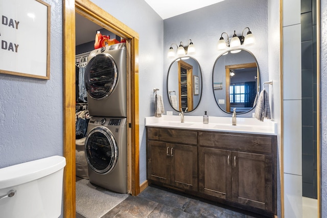 bathroom featuring toilet, stacked washer / dryer, and vanity