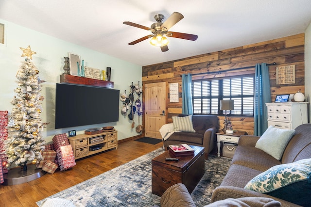 living room featuring ceiling fan, dark hardwood / wood-style flooring, and wood walls