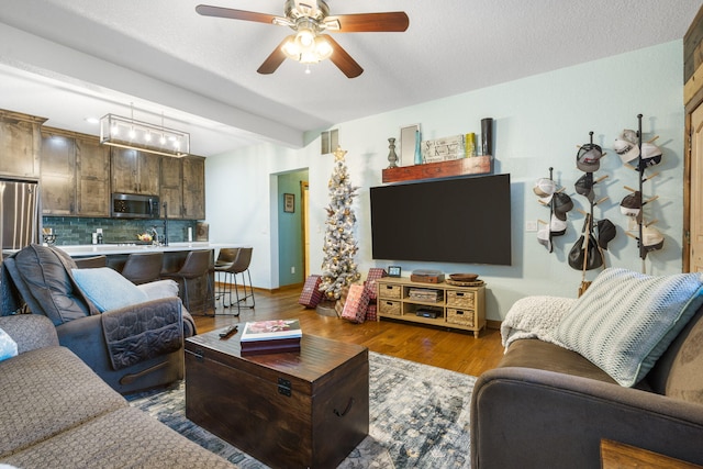 living room featuring a textured ceiling, dark wood-type flooring, and ceiling fan