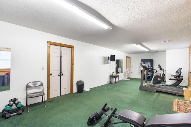 workout area with dark carpet and a textured ceiling