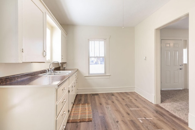 kitchen with white cabinetry, sink, and light hardwood / wood-style floors