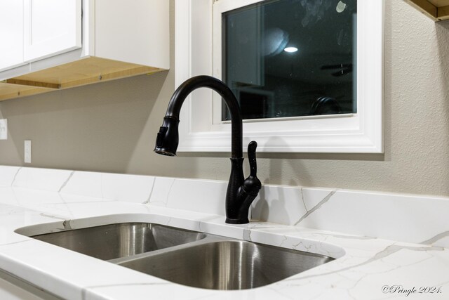 room details with light stone countertops, white cabinets, and sink