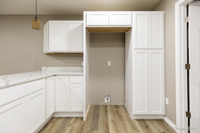 kitchen featuring light stone countertops, light hardwood / wood-style floors, white cabinetry, and hanging light fixtures