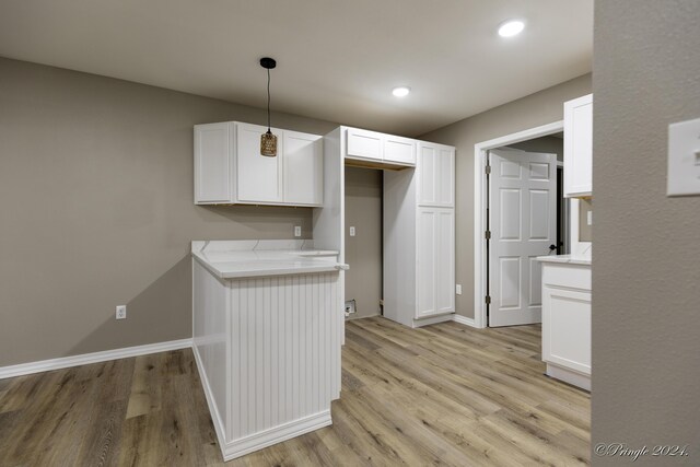 kitchen with white cabinetry, light hardwood / wood-style flooring, and hanging light fixtures