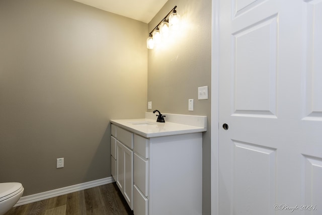 bathroom with toilet, vanity, and hardwood / wood-style flooring