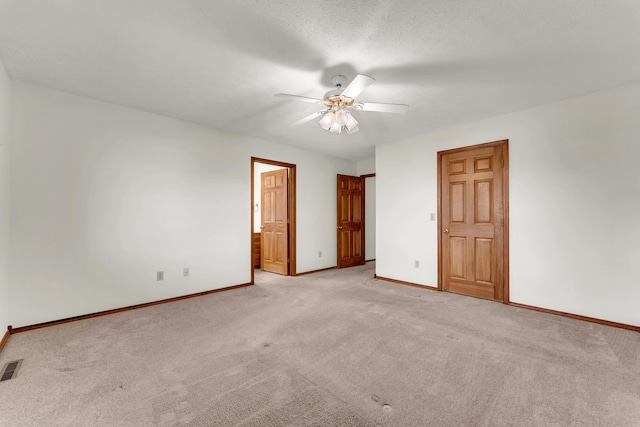 unfurnished bedroom featuring a textured ceiling, light colored carpet, ceiling fan, and ensuite bathroom