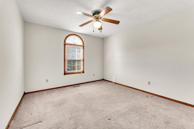 spare room featuring a textured ceiling, carpet floors, and ceiling fan