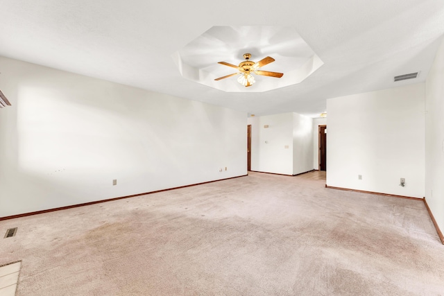 carpeted spare room featuring ceiling fan and a raised ceiling