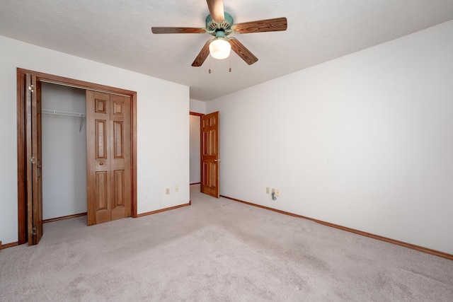 unfurnished bedroom with light carpet, a textured ceiling, a closet, and ceiling fan