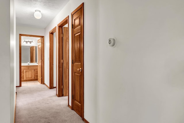 hallway with light carpet and a textured ceiling