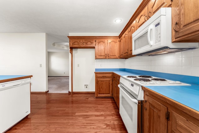 kitchen with backsplash, light hardwood / wood-style flooring, and white appliances