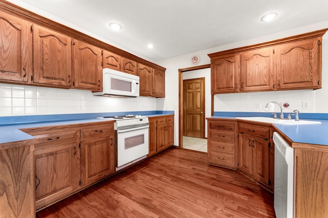 kitchen with hardwood / wood-style flooring, decorative backsplash, white appliances, and sink