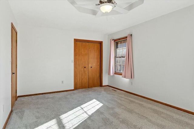 unfurnished bedroom featuring ceiling fan, light carpet, and a closet