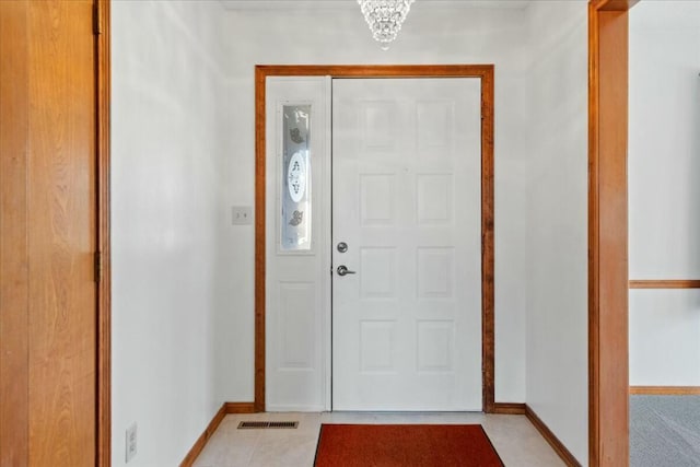 tiled entryway with a notable chandelier