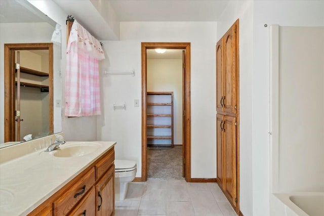 bathroom with tile patterned flooring, vanity, a bathtub, and toilet