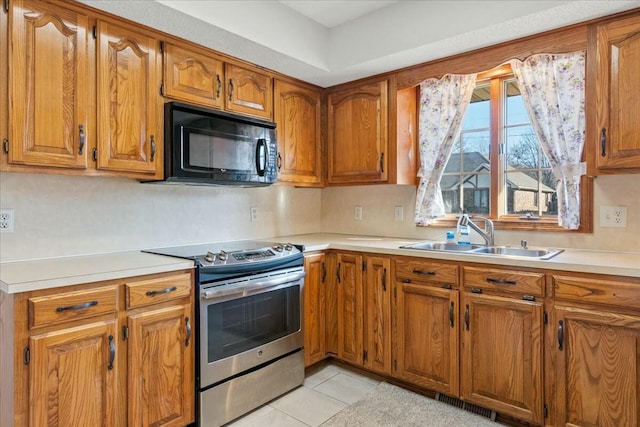 kitchen featuring stainless steel electric stove, light tile patterned floors, and sink