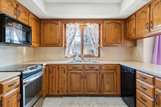 kitchen with black appliances, light tile patterned flooring, a raised ceiling, and sink