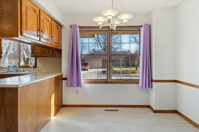 kitchen with pendant lighting, an inviting chandelier, a wealth of natural light, and sink