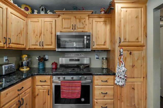 kitchen with dark stone countertops and appliances with stainless steel finishes