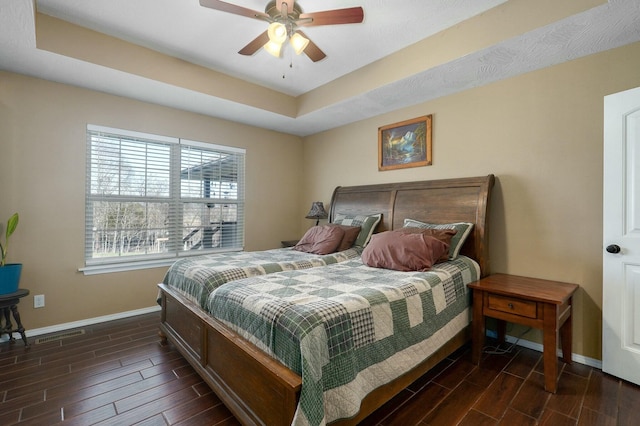 bedroom with dark hardwood / wood-style floors, a raised ceiling, and ceiling fan