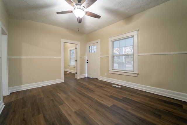 unfurnished room with a textured ceiling, dark hardwood / wood-style flooring, ceiling fan, and wooden walls