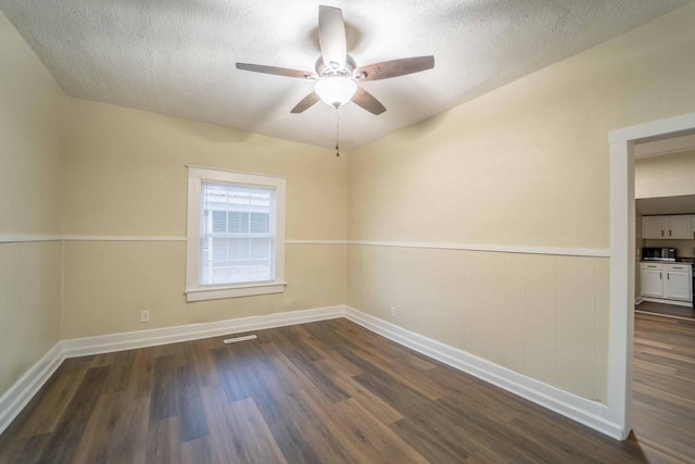 empty room with dark hardwood / wood-style flooring, a textured ceiling, and ceiling fan