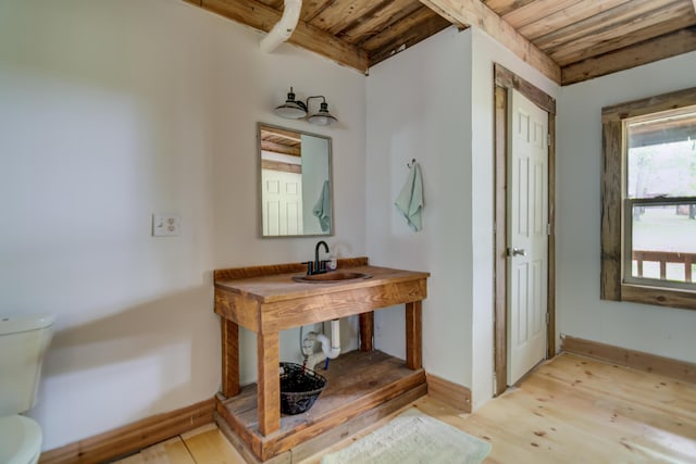 bathroom featuring hardwood / wood-style floors, toilet, wooden ceiling, and sink