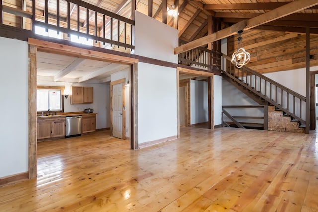 unfurnished living room featuring beamed ceiling and light hardwood / wood-style flooring