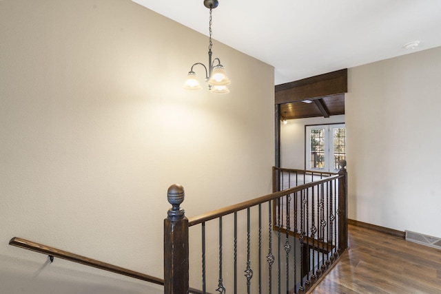 stairway featuring a chandelier, wood-type flooring, and lofted ceiling with beams