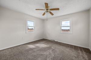 unfurnished room featuring dark colored carpet, ceiling fan, and a wealth of natural light