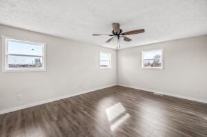 empty room featuring ceiling fan, dark hardwood / wood-style flooring, and a textured ceiling