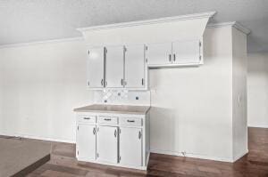 kitchen featuring dark wood-type flooring, white cabinetry, and ornamental molding