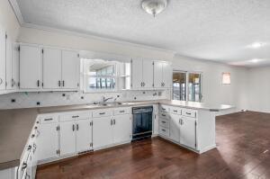 9800 Red Spring Rd, Mountain Grove, MO 65711 - kitchen with a peninsula, dishwasher, ornamental molding, white cabinets, and dark wood finished floors
