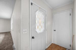 carpeted entrance foyer with crown molding