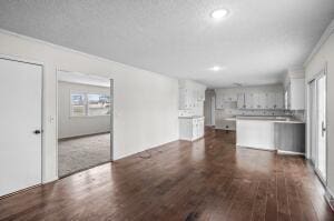 unfurnished living room featuring dark wood-type flooring and ornamental molding