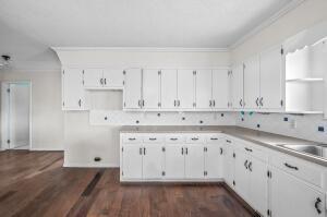 kitchen featuring dark hardwood / wood-style floors, white cabinetry, ornamental molding, and sink