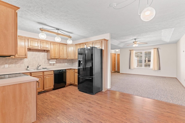 kitchen with a textured ceiling, light hardwood / wood-style floors, hanging light fixtures, and black appliances