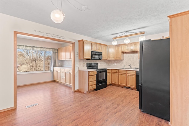 kitchen with pendant lighting, backsplash, black appliances, light wood-type flooring, and light brown cabinetry