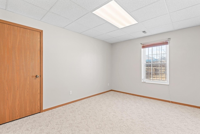 carpeted spare room with a drop ceiling