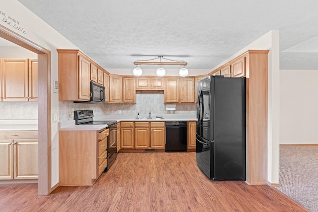 kitchen with backsplash, black appliances, sink, light hardwood / wood-style flooring, and a textured ceiling