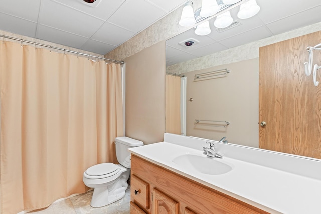 bathroom featuring tile patterned flooring, vanity, toilet, and a paneled ceiling