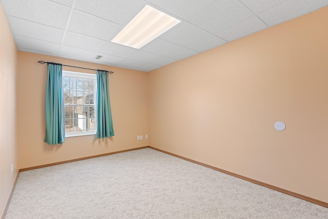 carpeted spare room featuring a drop ceiling