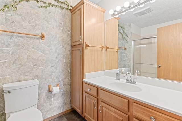 bathroom with vanity, toilet, a textured ceiling, tile walls, and a shower with shower door