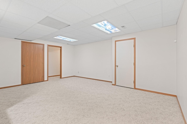 basement with a drop ceiling and light colored carpet